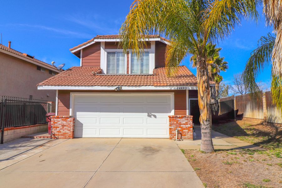 A suburban home with a tile roof and palm trees